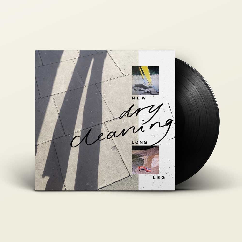 Dry Cleaning - New Long Leg (Vinyl LP): A vinyl record partially pulled from its album cover, shown on a light, warm-grey background. The cover features a split design: one side shows long shadows on pavement, and the other has a white panel with small artwork and the text -DRY CLEANING - NEW LONG LEG'.