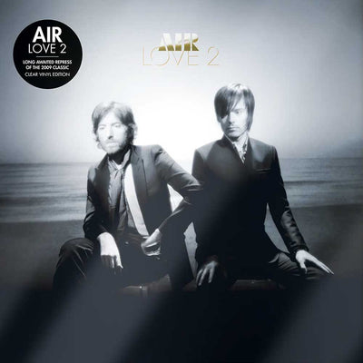 Air - Love 2 (Vinyl 2LP Clear Limited Edition) Air Love 2 vinyl record cover art featuring two men in suits seated against a misty outdoor background, with the title 'AIR LOVE 2' at the top and a black 'AIR LOVE 2' sticker on the upper left.