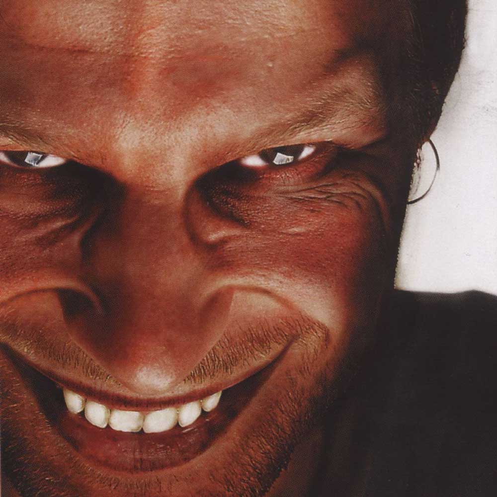Aphex Twin - Richard D. James Album (Vinyl LP 180g) Record album cover showing a close-up portrait of a man with a wide, toothy grin, showing his eyes, nose, mouth, and stubble against a dark shirt and light background.
