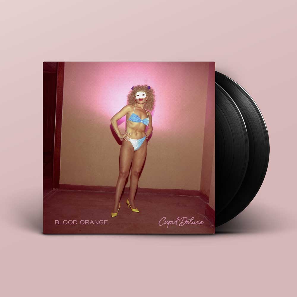 Blood Orange - Cupid Deluxe (Vinyl 2LP) A vinyl record album set shown on a dusty pink background. The square album cover features a person in a light blue bikini posing in a room with pink lighting, and the black vinyl records are partially visible behind the cover.