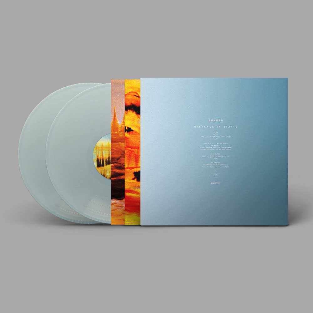 Bonobo - Distance In Static (Vinyl 2LP Pastel Blue) A vinyl record album shown on a plain gray background, with two translucent pale blue records partially visible behind a blue sleeve. The sleeve has small white text and a vertical multicolor scenic strip near the center.