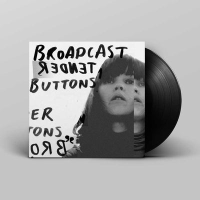 Broadcast - Tender Buttons (Vinyl LP): A vinyl record partially pulled from its sleeve, shown on a light grey background. The sleeve is black-and-white with handwritten text 'Broadcast - Tender Buttons' and a portrait, and the record itself is black.
