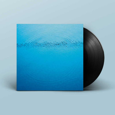 Caribou - Suddenly (Vinyl LP) A vinyl record partially pulled from its sleeve, showing a bright blue water-ripple design on the cover with a black record visible behind it, set against a light blue background.