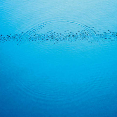 Caribou - Suddenly (Vinyl LP) A close-up photograph of bright blue water with a ripple pattern created by a drop falling on the surface.