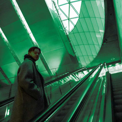 DJ Seinfield - If This Is It (Vinyl LP Transparent Green) Person standing on an escalator in a modern building with green lighting