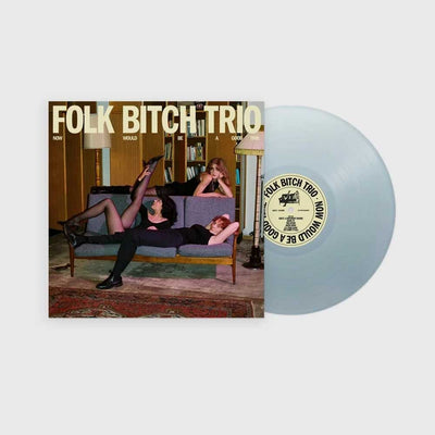 Folk Bitch Trio - Now Would Be A Good Time (Vinyl LP Sky Blue Opaque) A vinyl record album shown on a light gray background, with the printed cover to the left and the translucent pale blue record partially visible to the right. The cover reads 'FOLK BITCH TRIO' and features a retro indoor scene with three women lounging on a couch.