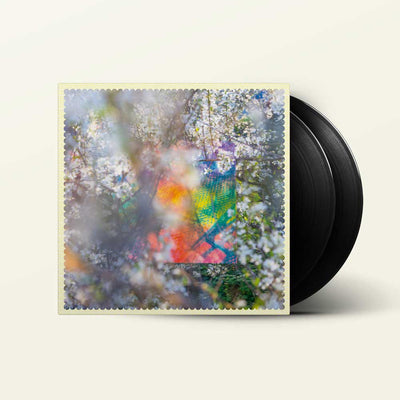 Four Tet - Sixteen Oceans (Vinyl 2LP) A vinyl record partially pulled from its sleeve, showing a colorful abstract floral artwork with white blossoms and a rainbow-like center, alongside a black record on a light cream background.