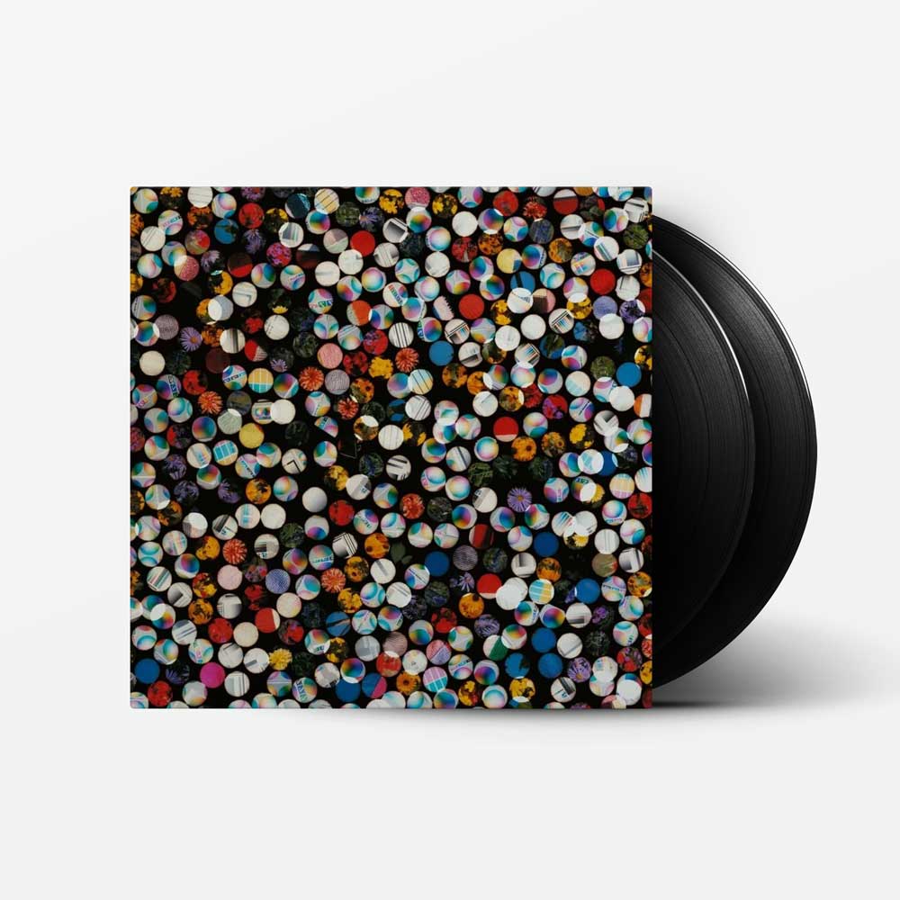 Four Tet - There Is Love In You (Vinyl 2LP 2026 Repress) A vinyl record partially pulled from its sleeve, showing a black disc and a square album cover covered in dense multicolored circular patterns on a light gray background.
