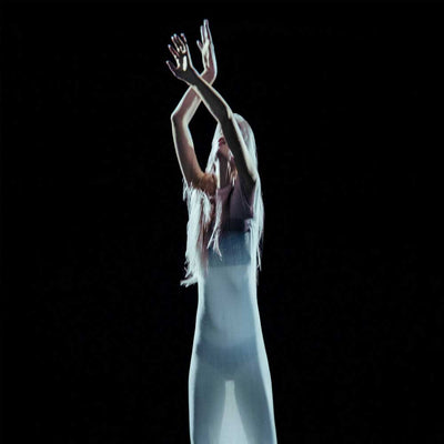 Kelly Moran - Don't Trust Mirrors (Vinyl LP) A person with long light hair stands against a black background with arms raised overhead, wearing a sheer white or pale gray bodysuit or dress with a dark top.