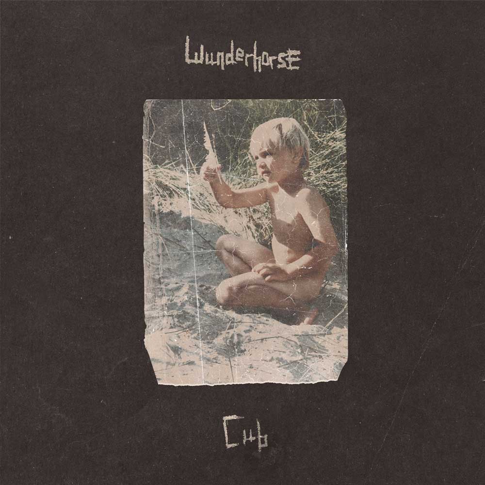 Wunderhorse - Cub (Vinyl LP Crystal Clear) Album cover for 'Club' by the band 'Wunderhorse', featuring a central vintage-style photograph of a young child sitting outdoors on a sandy surface, set against a dark textured background with the band name at the top and the album title at the bottom.