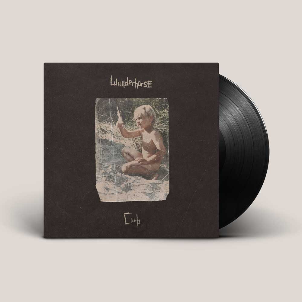 Wunderhorse - Cub (Vinyl LP Crystal Clear)A vinyl record partially pulled from its square album cover, shown on a light warm-gray background. The cover is dark brown with a central vintage-style photo of a child sitting on a swing, and the text 'Wunderhorse' appears near the top.